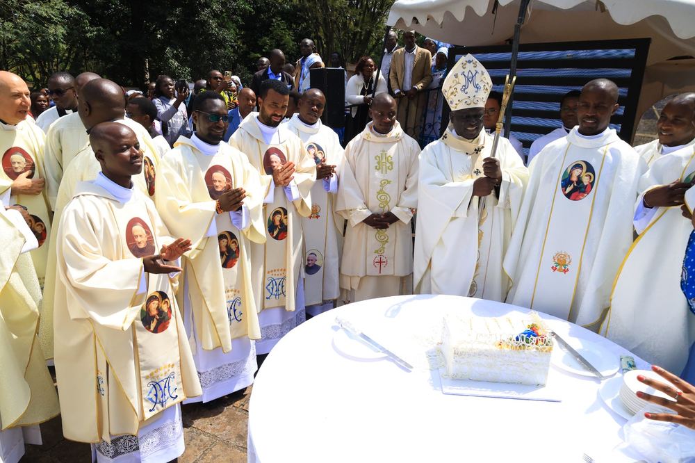 Archbishop Philip Anyolo with the newly ordained around the celebration cake