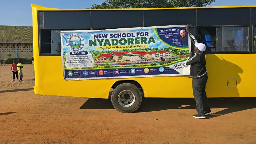 The &ldquo;New School for Nyadorera&rdquo; banner being fixed on the school bus