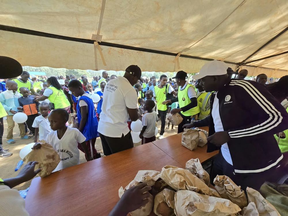 Volunteers handing out packed snacks to children under the tent