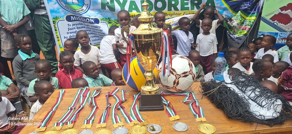Trophy, medals, volleyball, football and net displayed before the nursery children